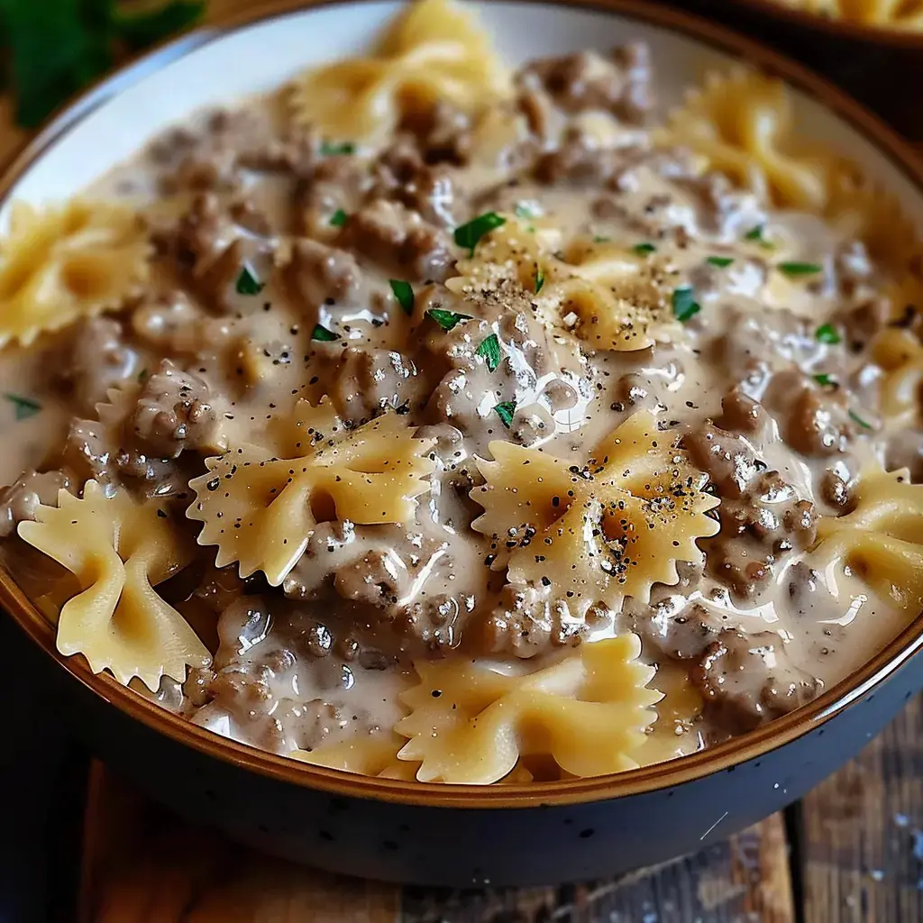 Un bol de farfalles nappées d’une sauce dessert à la viande hachée et agrémentées de persil et poivre.